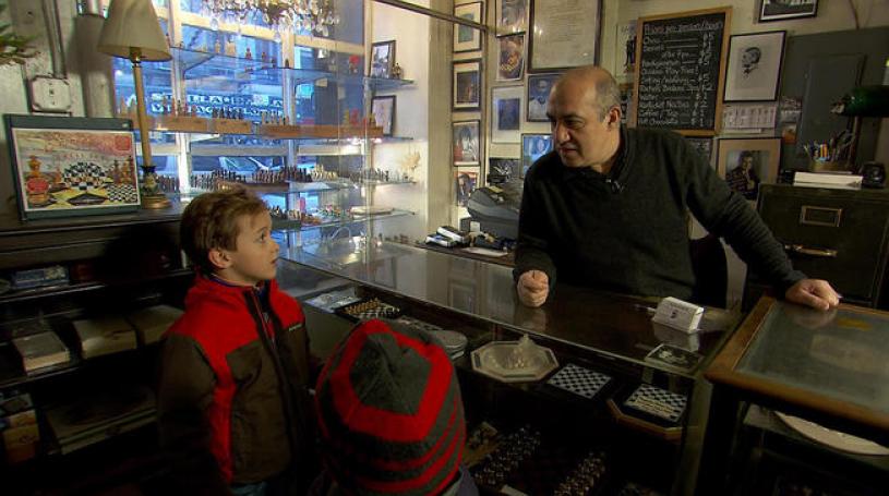 Chess Forum owner Imad Khachan talks shop with Oliver Armstrong, 8 and his brother Henry, 6.